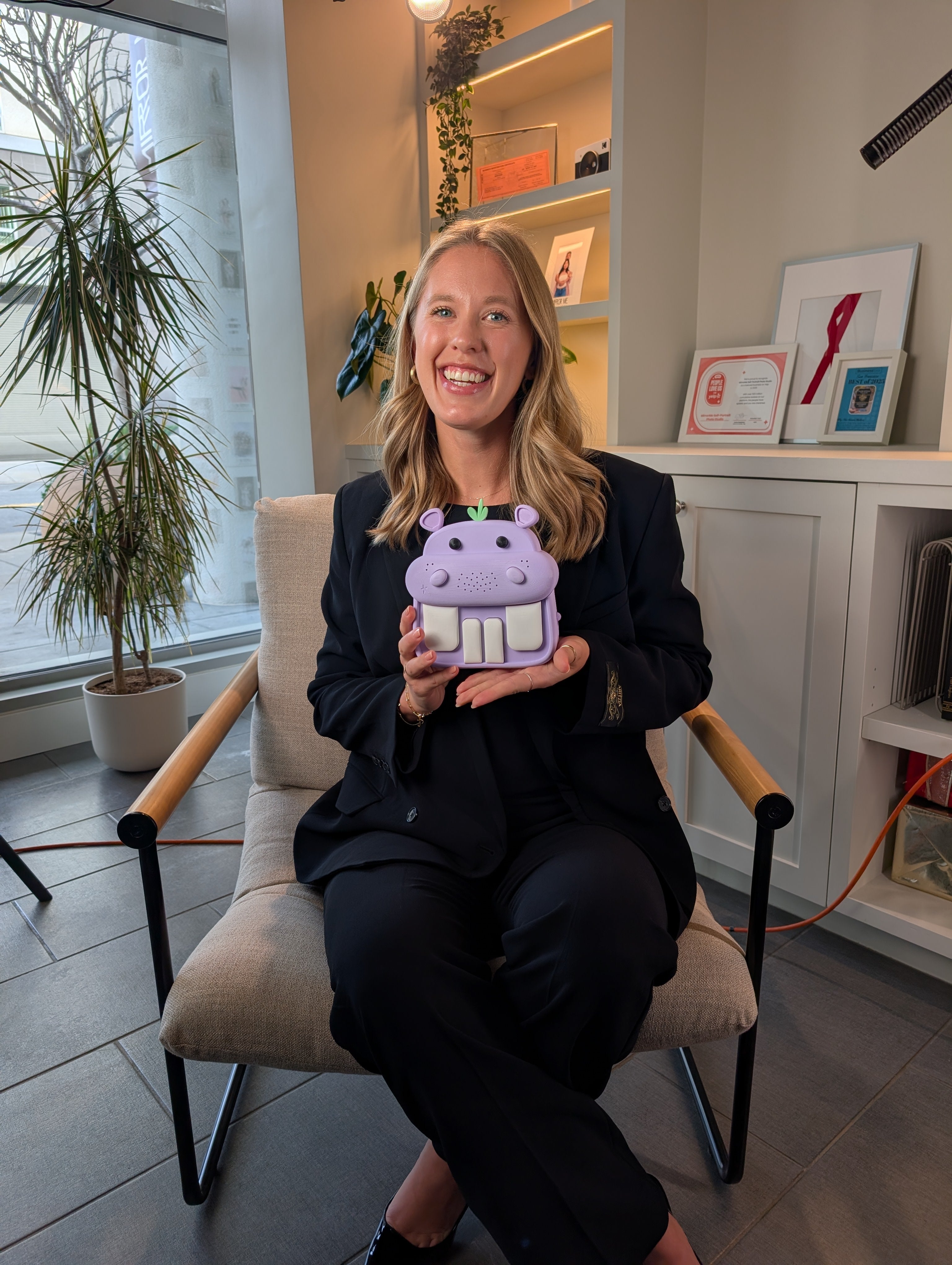 Person sitting in a chair holding a purple Harra the Hippo toy in an office setting